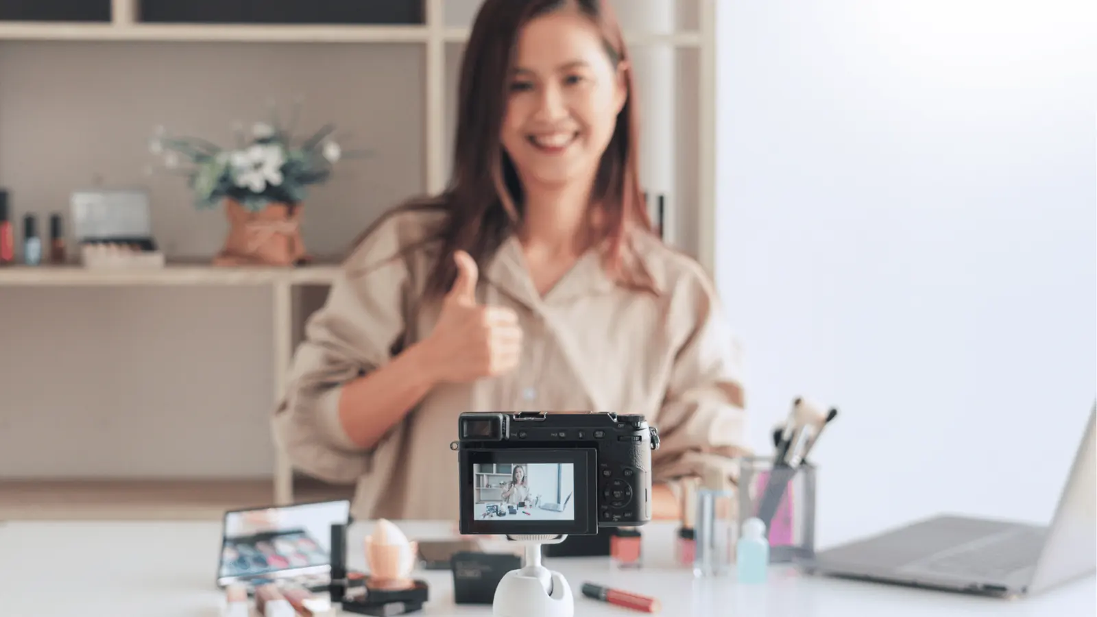 Smiling woman gives thumbs up while recording a makeup tutorial for publishing