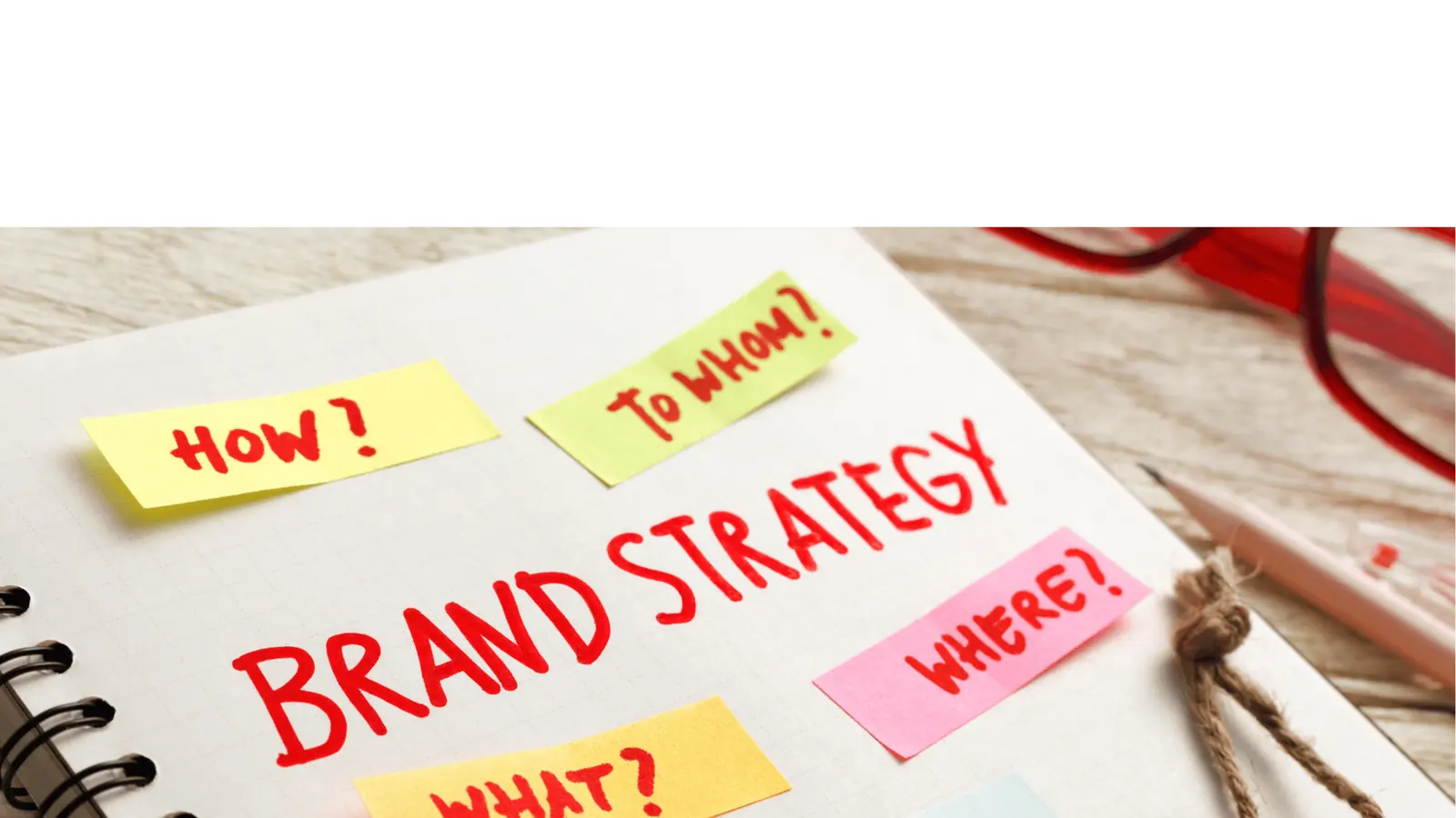 Notebook page reading BRAND STRATEGY with colorful sticky notes asking questions