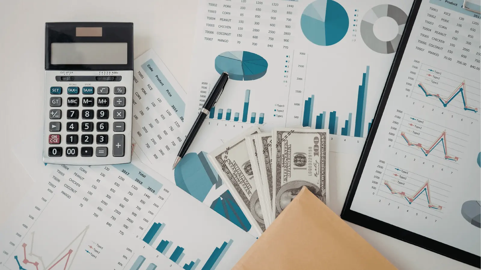 Calculator, pen, cash and printed financial charts spread on table