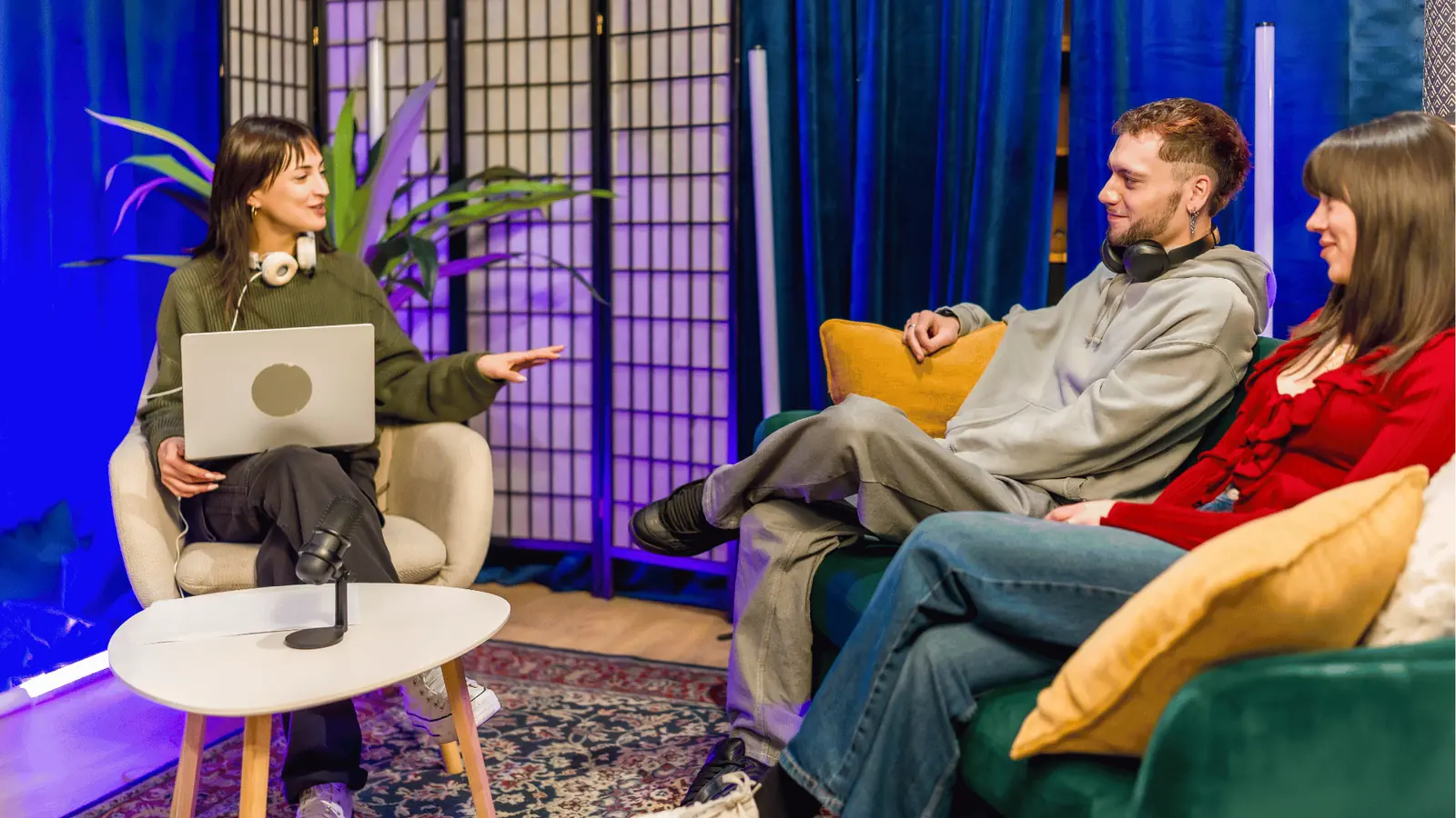 Three people in a cozy studio recording a casual podcast interview for community management