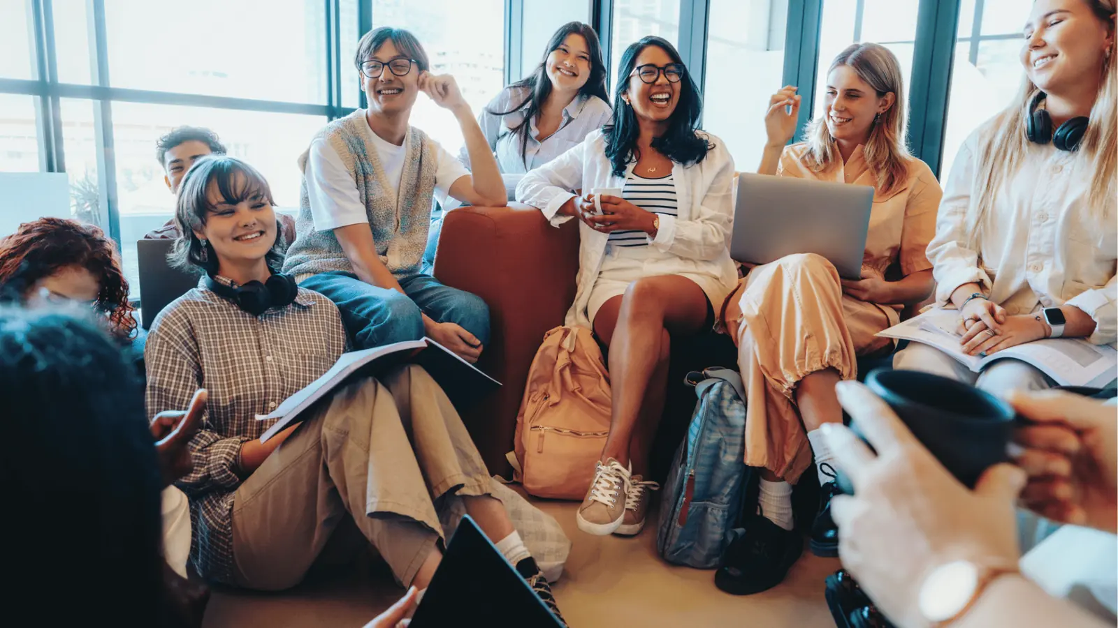 Group of young people sitting in casual meeting space smiling and talking