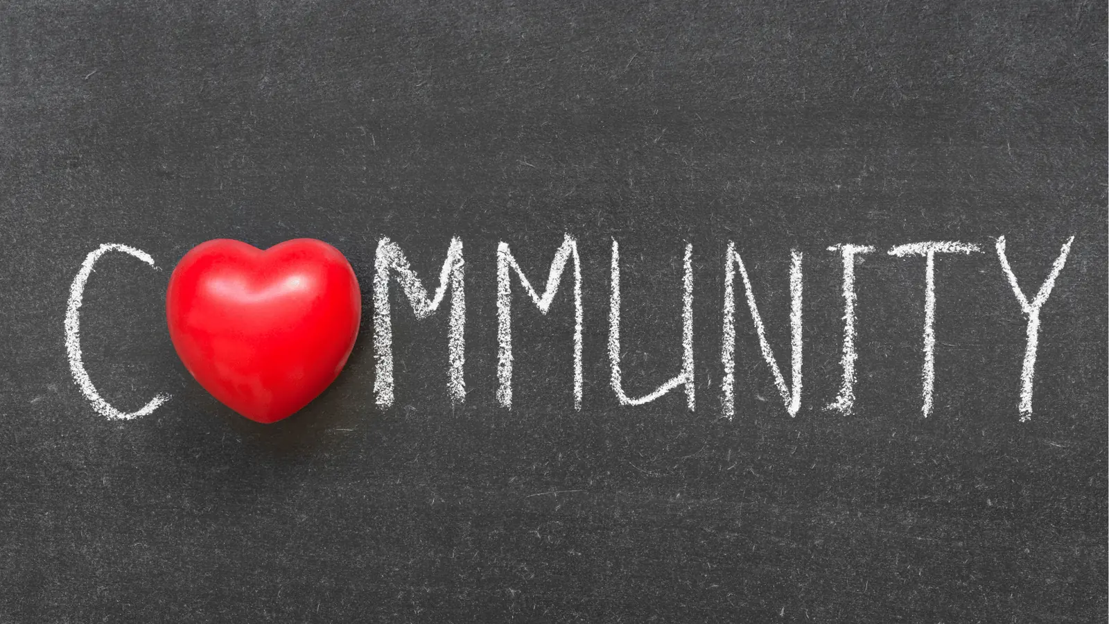 Red heart placed on a chalkboard spelling the word community in chalk for brand management