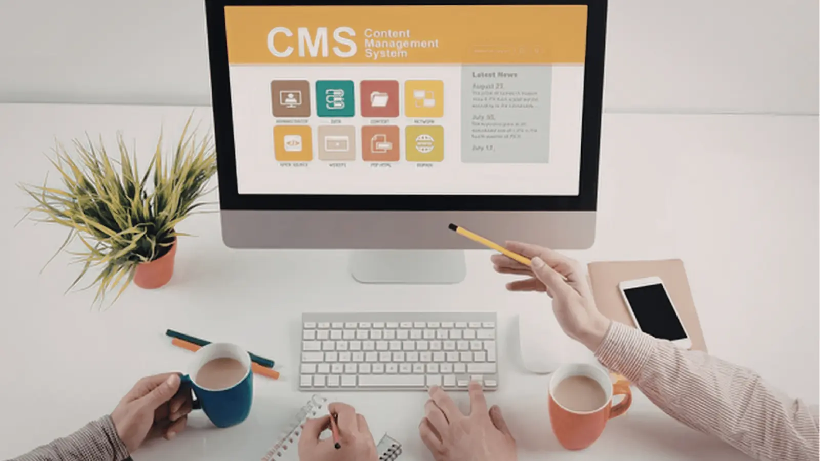 Desktop computer showing CMS screen on a tidy desk with hands and coffee for creative production