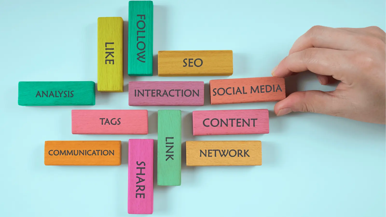 Hand arranging colorful wooden blocks labeled with social media marketing words