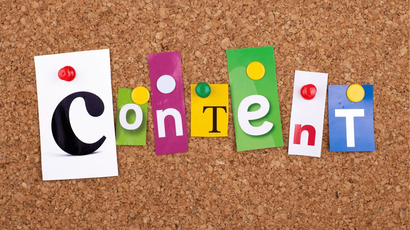 Corkboard with colorful cutout letters pinned spelling the word content