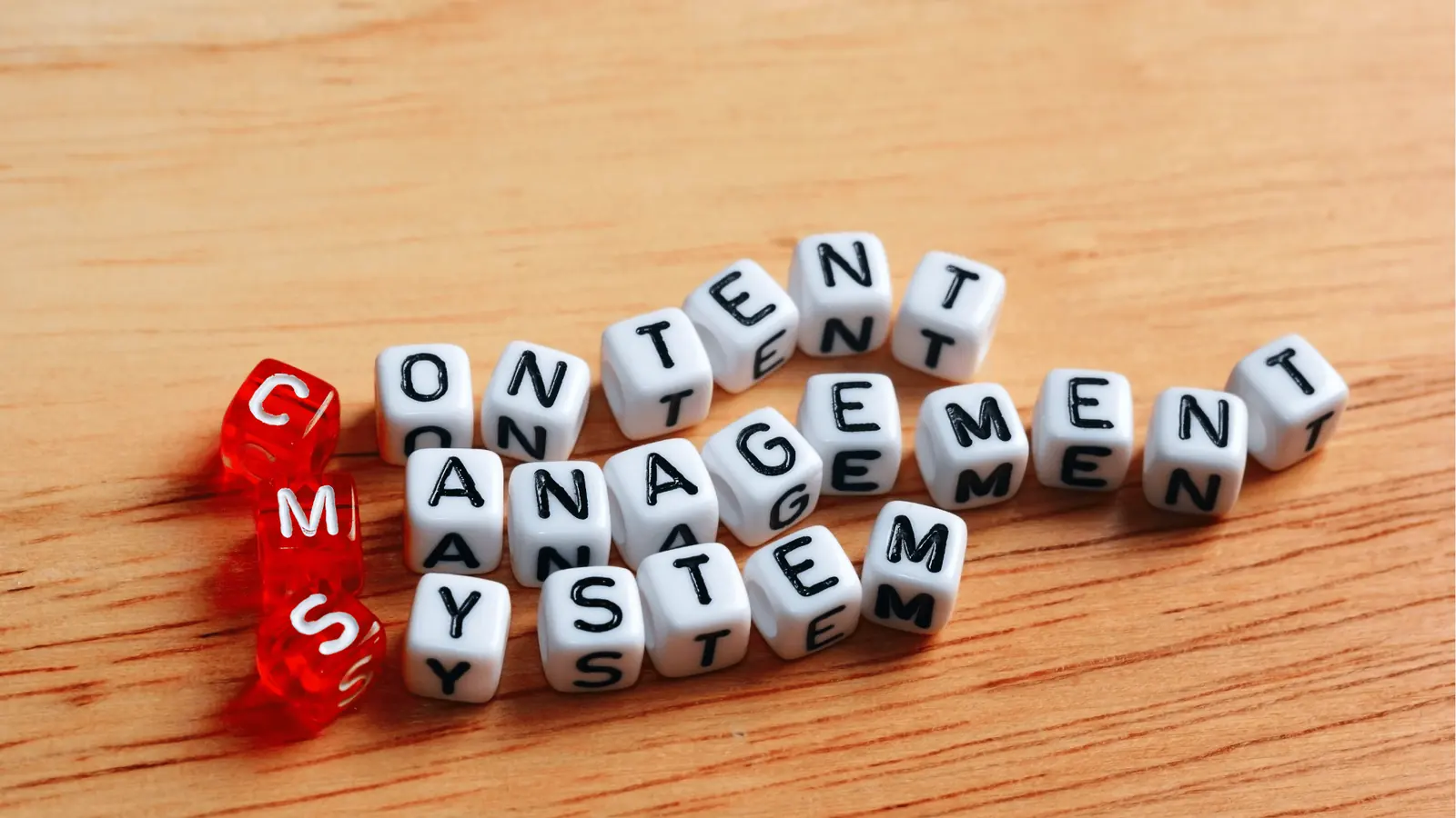 White letter cubes on wood spelling content management system with red CMS cubes