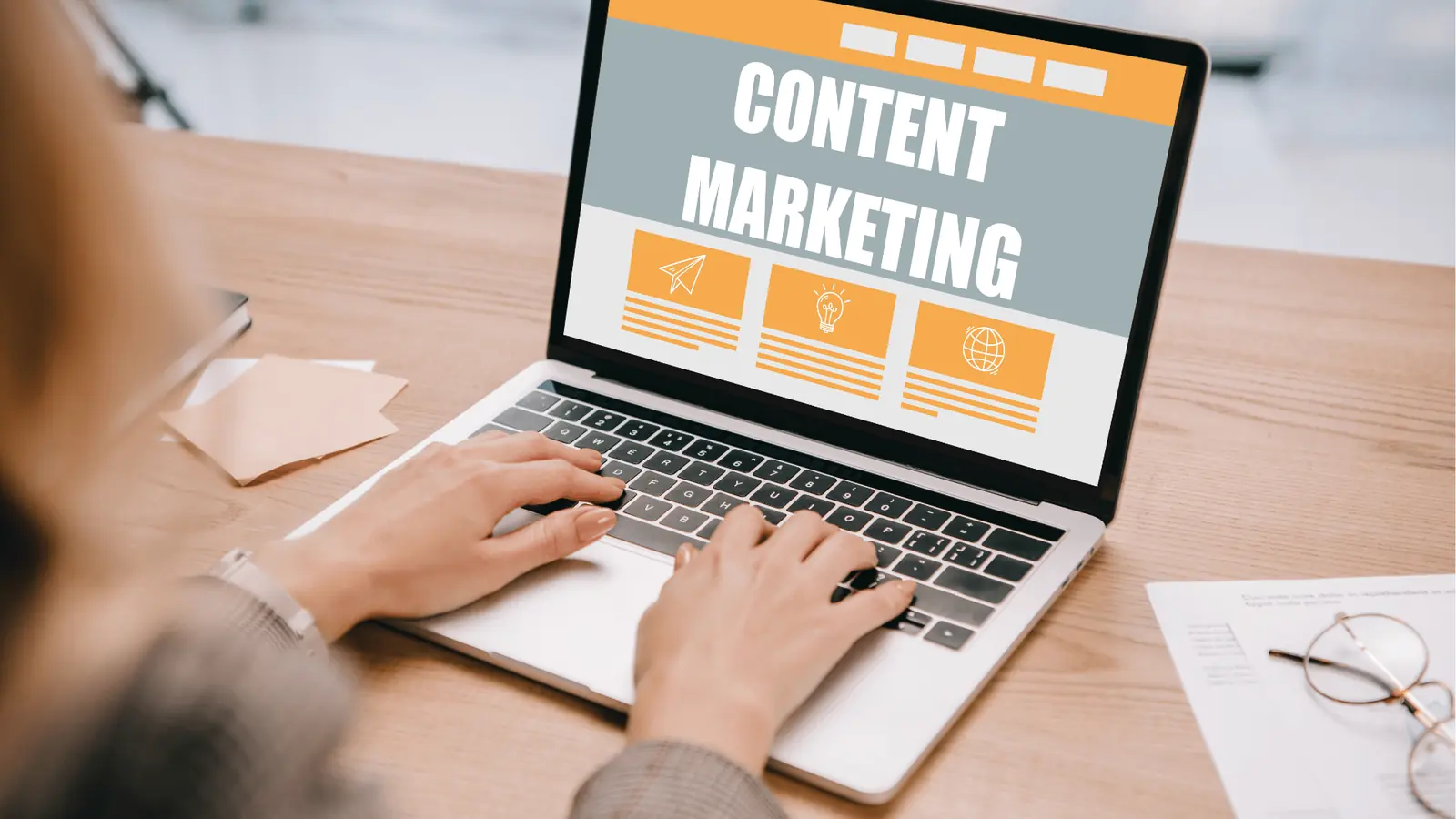 Hands typing on a laptop displaying a content marketing webpage on desk for publishing