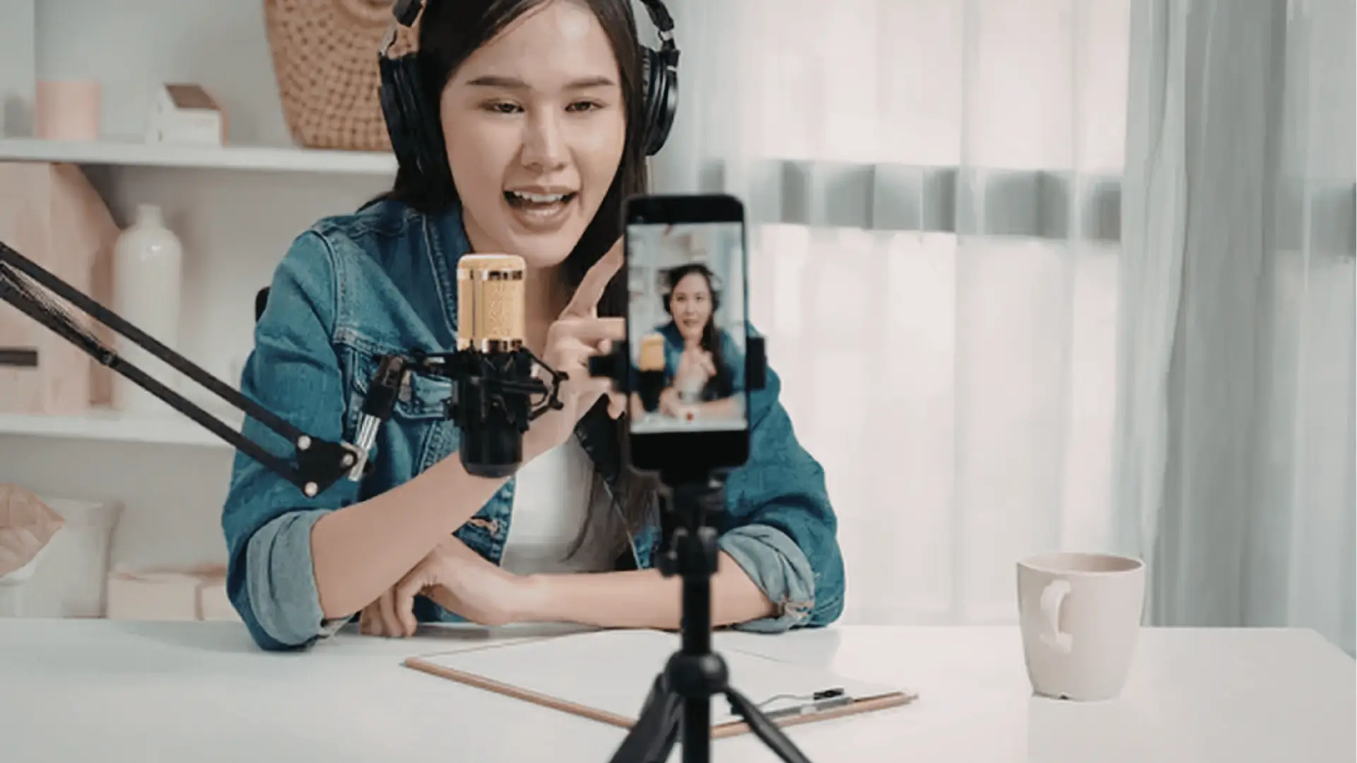 Woman recording a live video on smartphone with microphone and headphones