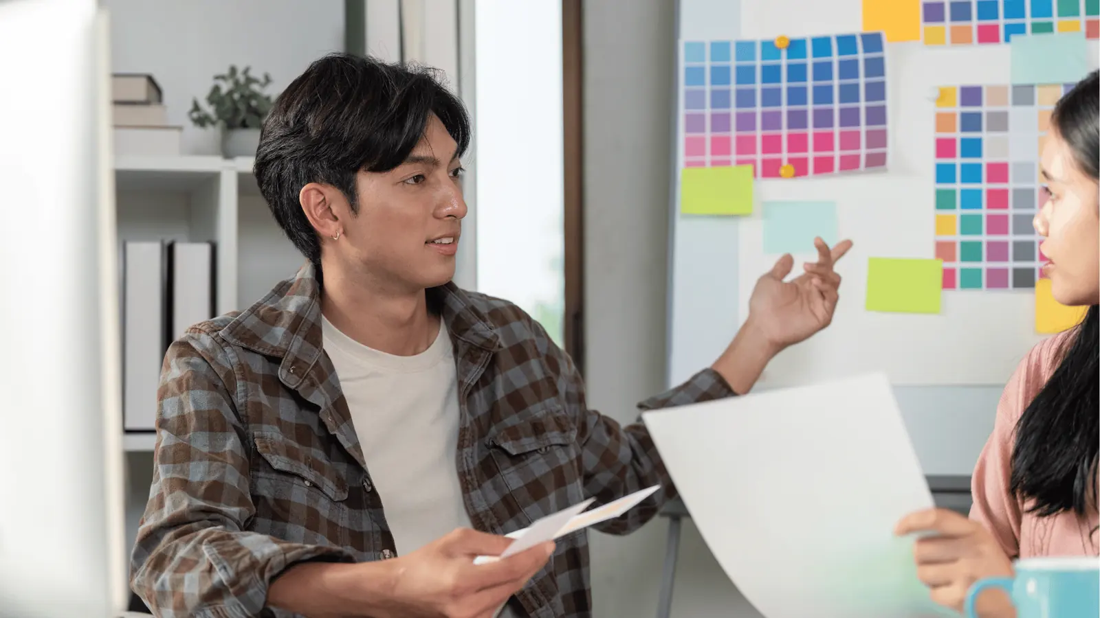 Two colleagues reviewing color swatches and printed pages in a design meeting
