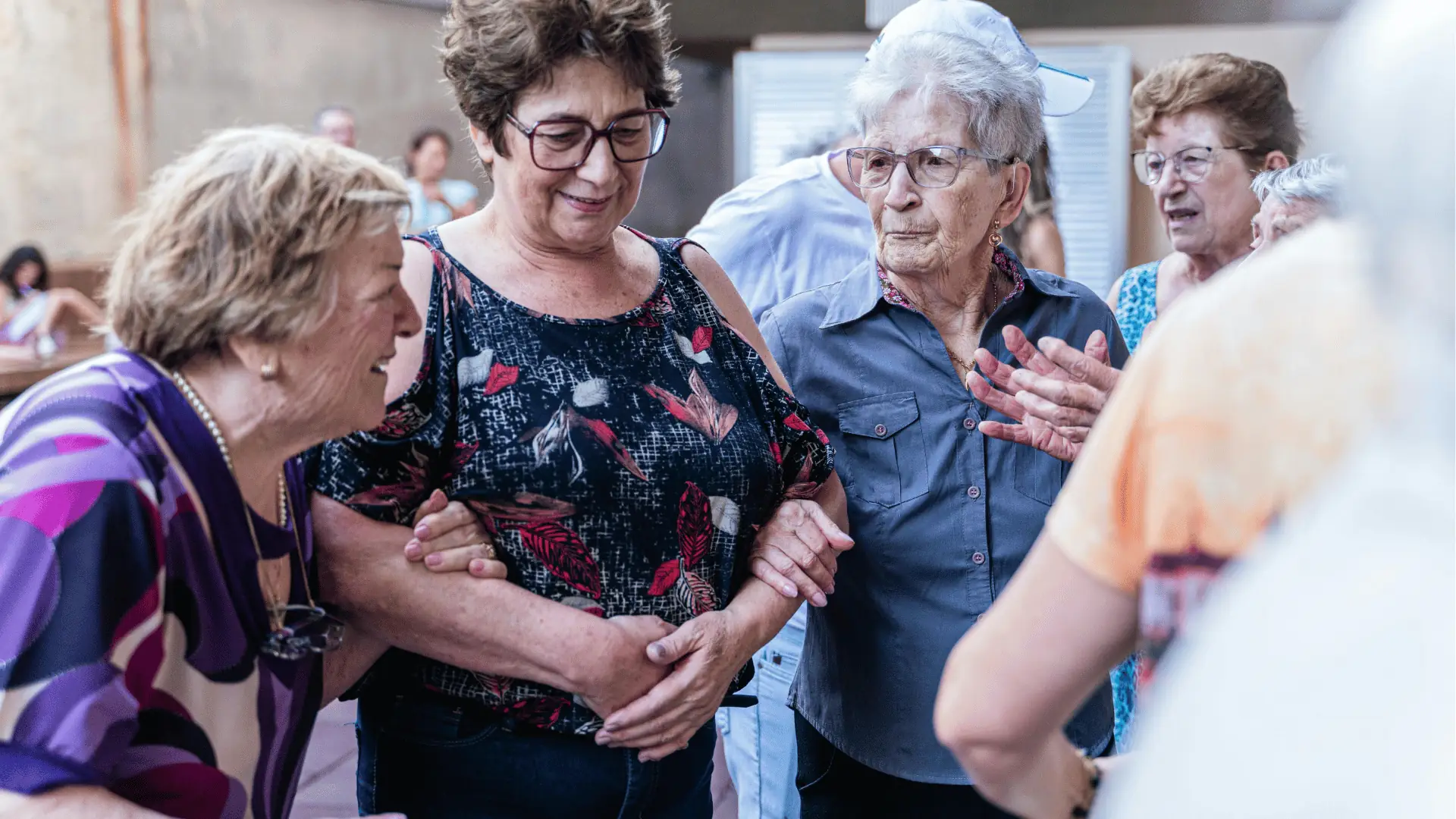 Group of elderly women linking arms and chatting at a social gathering
