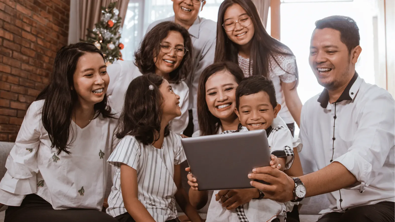 Multigenerational family smiling together while looking at a tablet screen