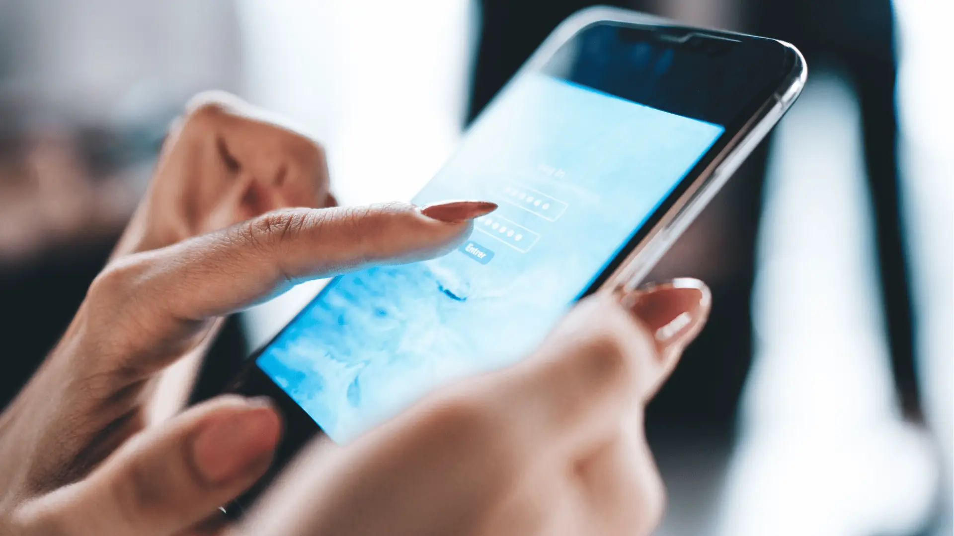 Close-up of hands tapping a smartphone showing a login screen