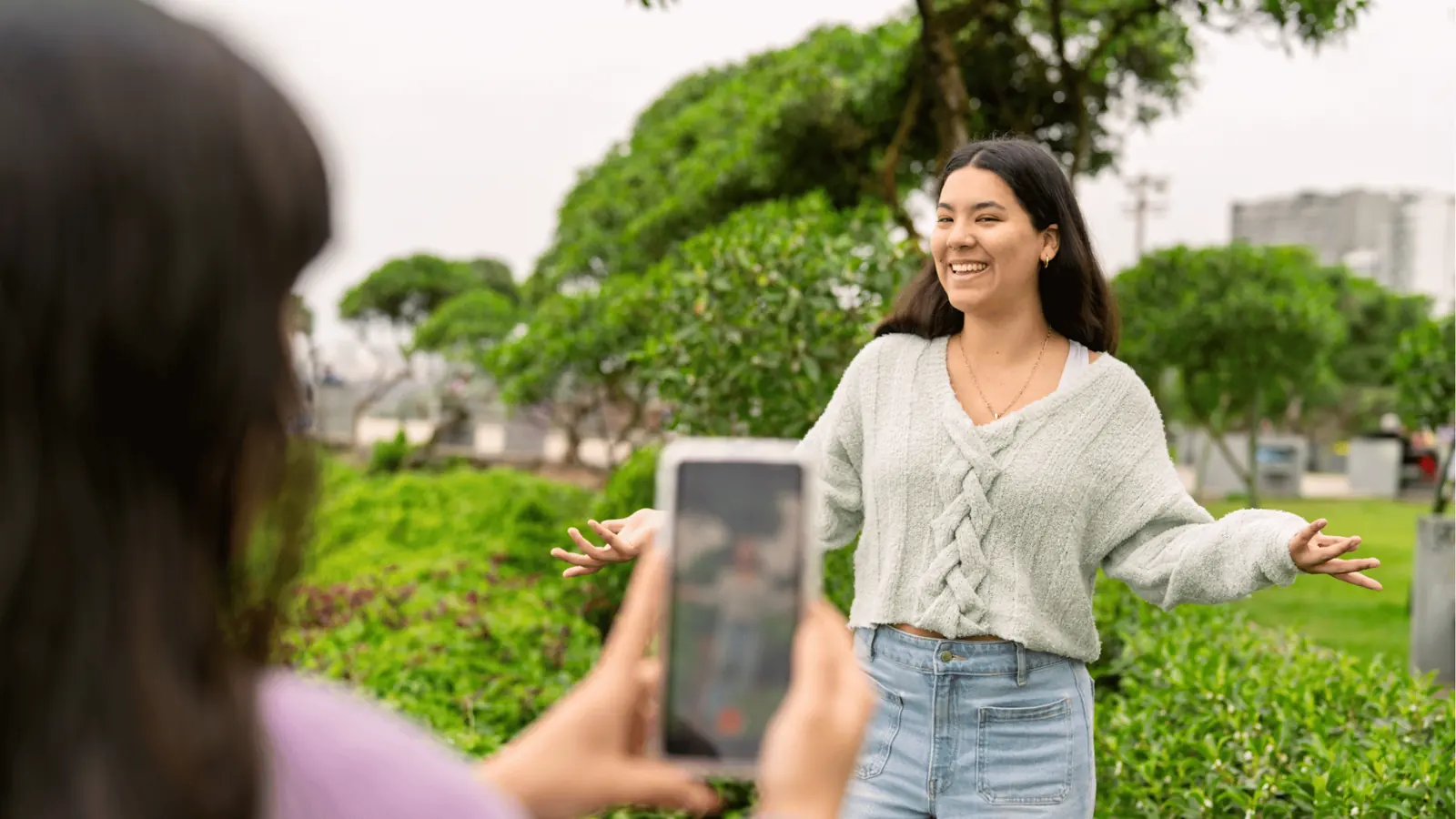 Young woman smiling and posing while friend records her on phone