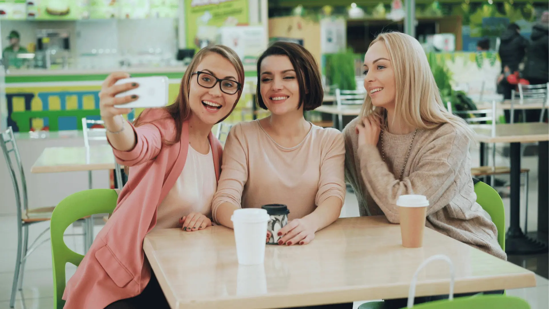 Colleagues smiling for a selfie in a cafe