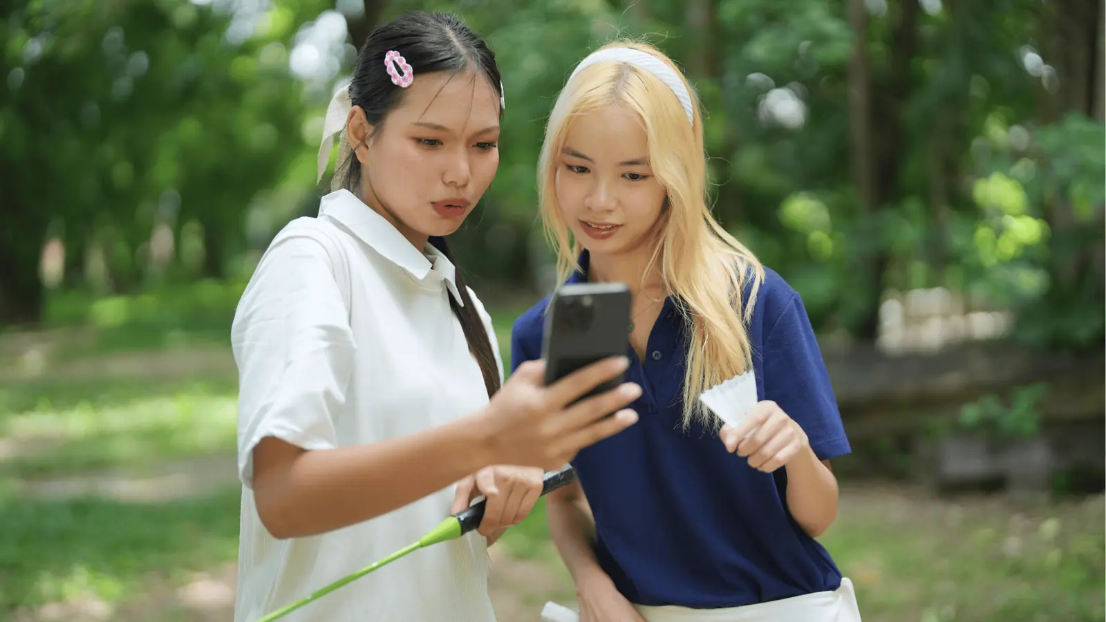 Friends smiling at a phone outdoors