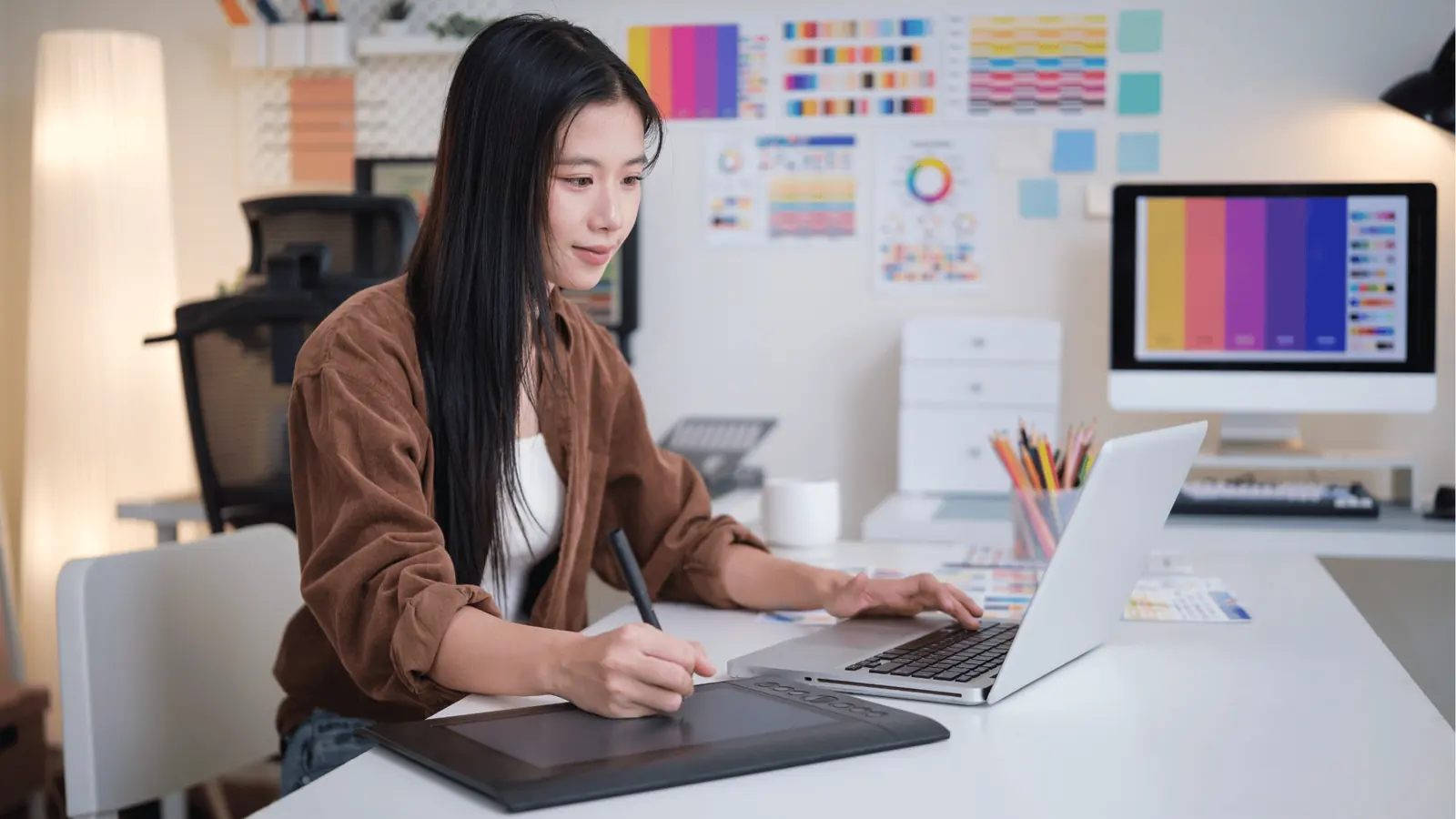 Designer resizing a social post layout across two monitors at a studio workstation