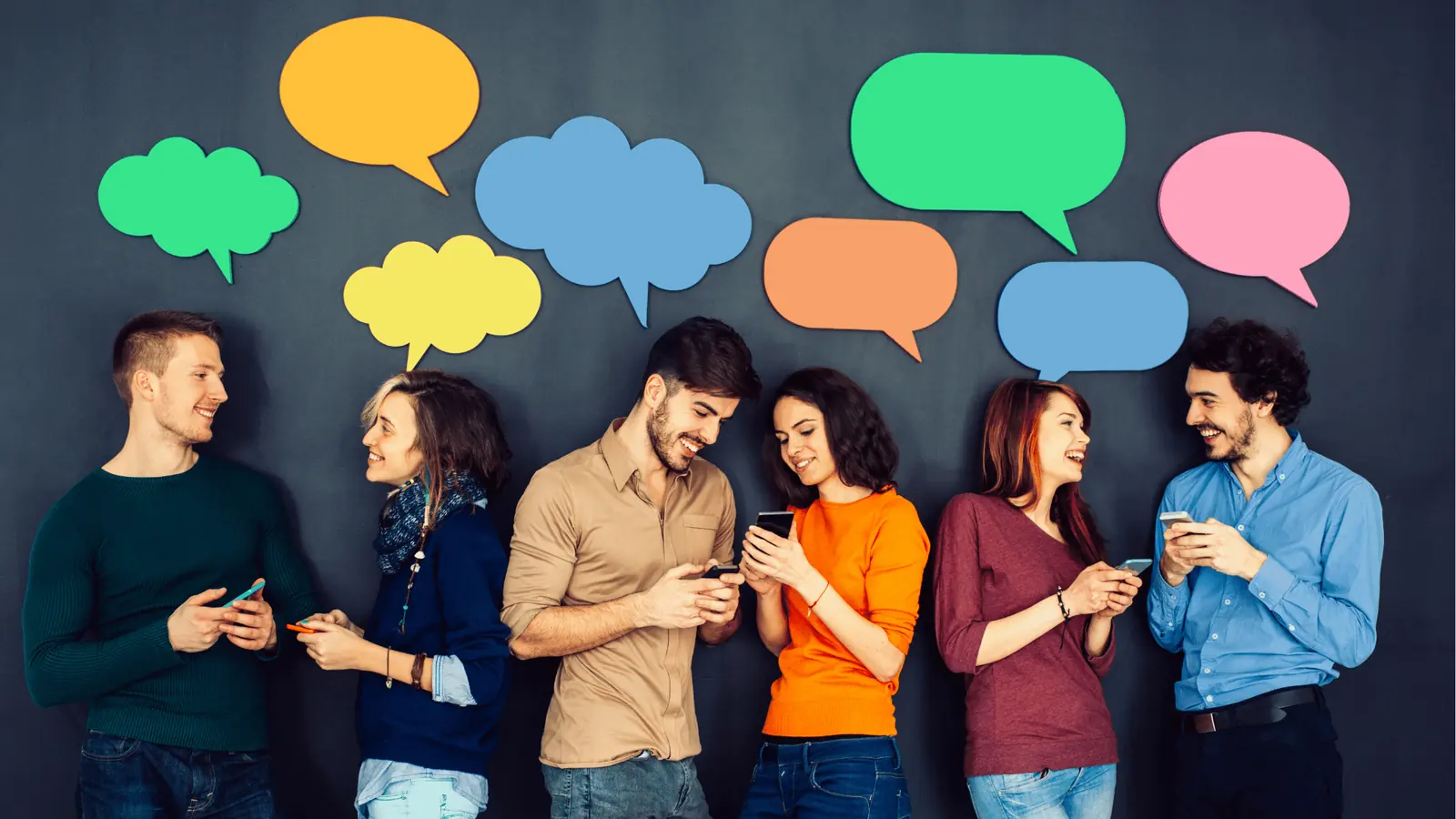Six people standing against a wall smiling and using smartphones under colorful speech bubbles for workflow