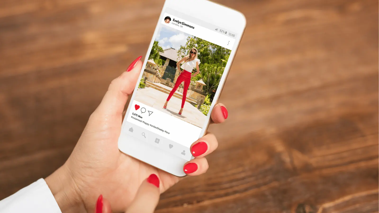 Hand holding a phone showing an Instagram profile grid of photo tiles