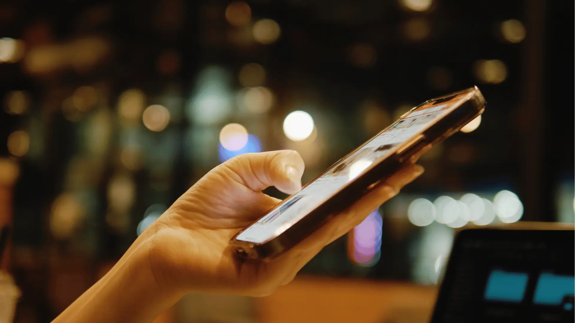 Close-up of hand tapping smartphone screen with blurred city lights background