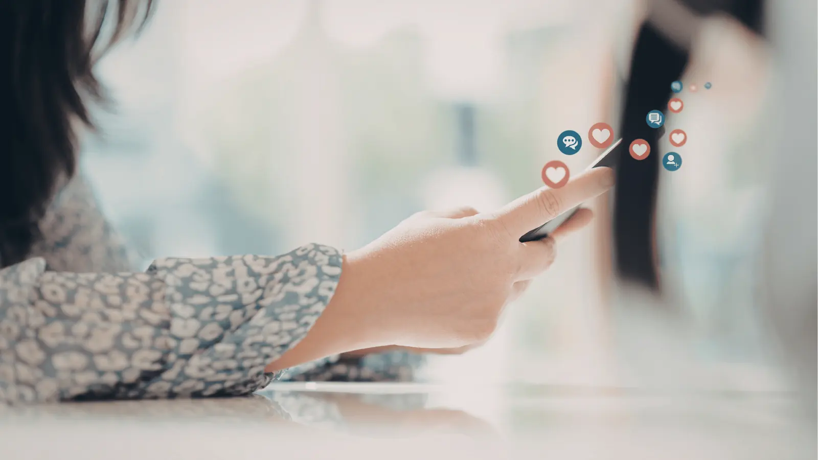 Hand holding smartphone with floating social media reaction icons
