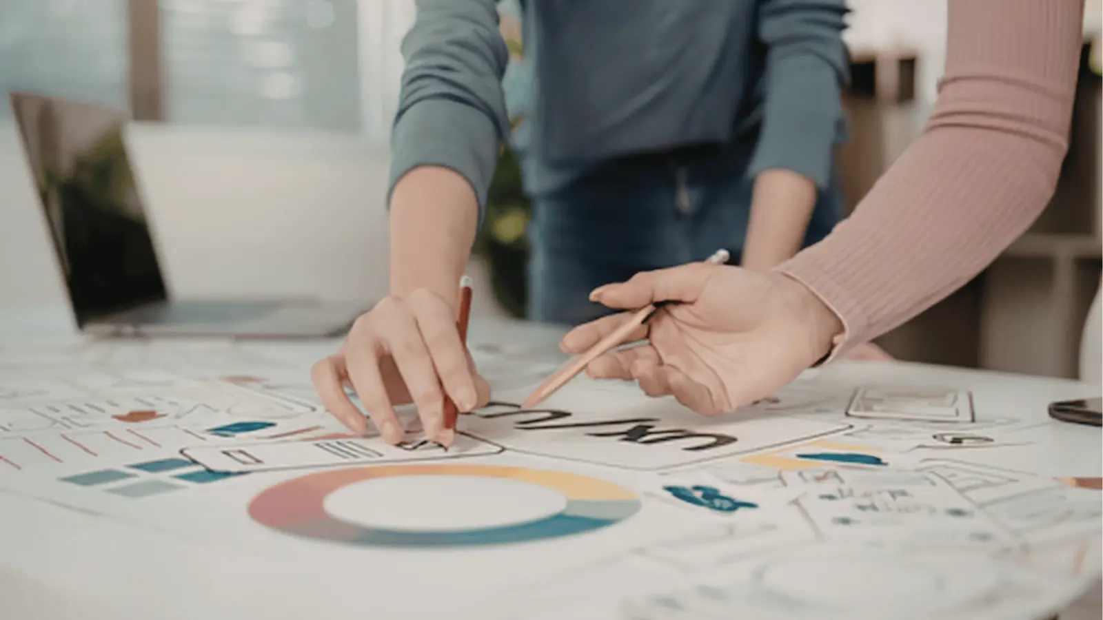 Two people sketching design ideas on a paper layout with color wheel