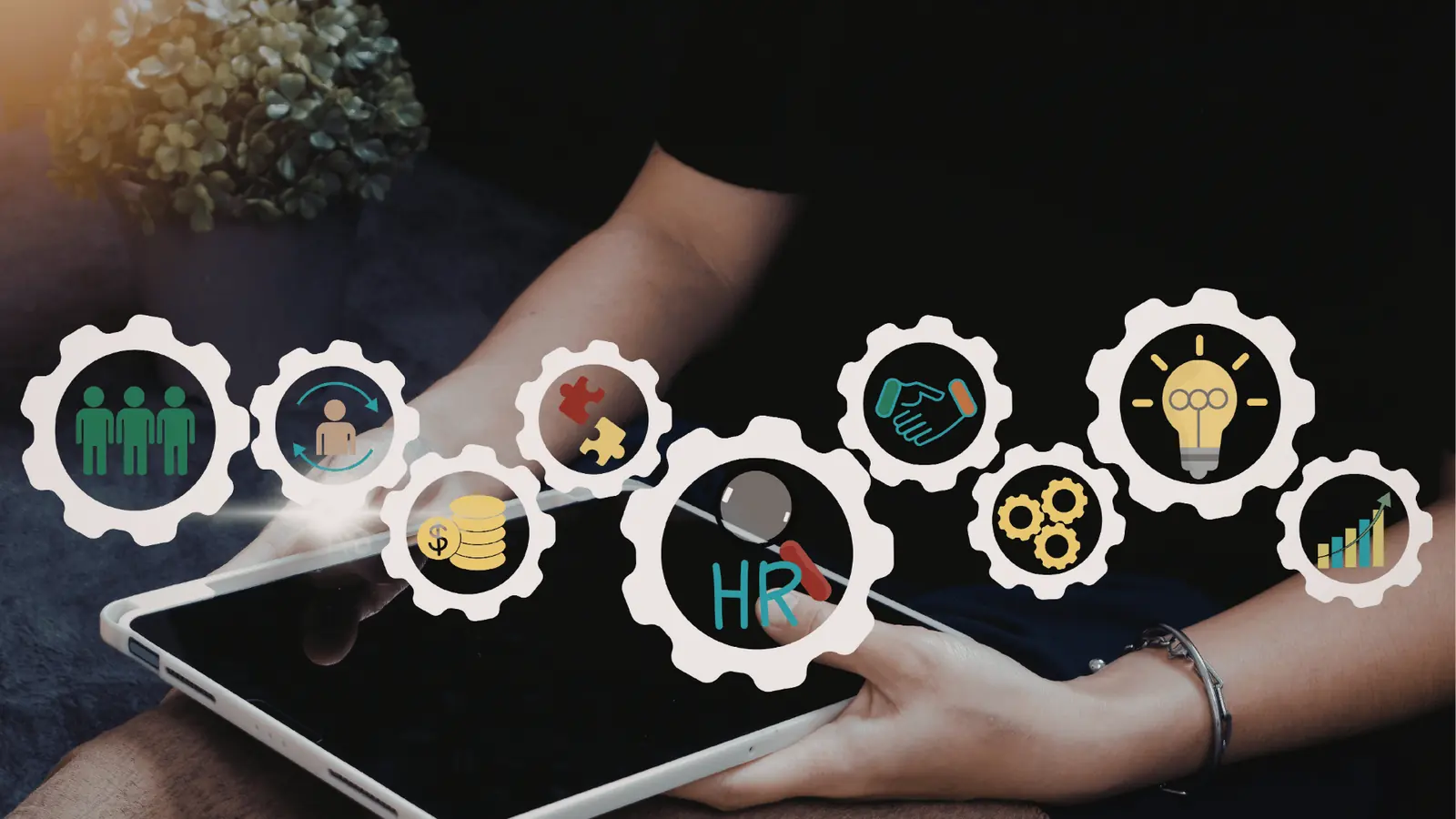 Hands holding a tablet with floating HR and business icon graphics