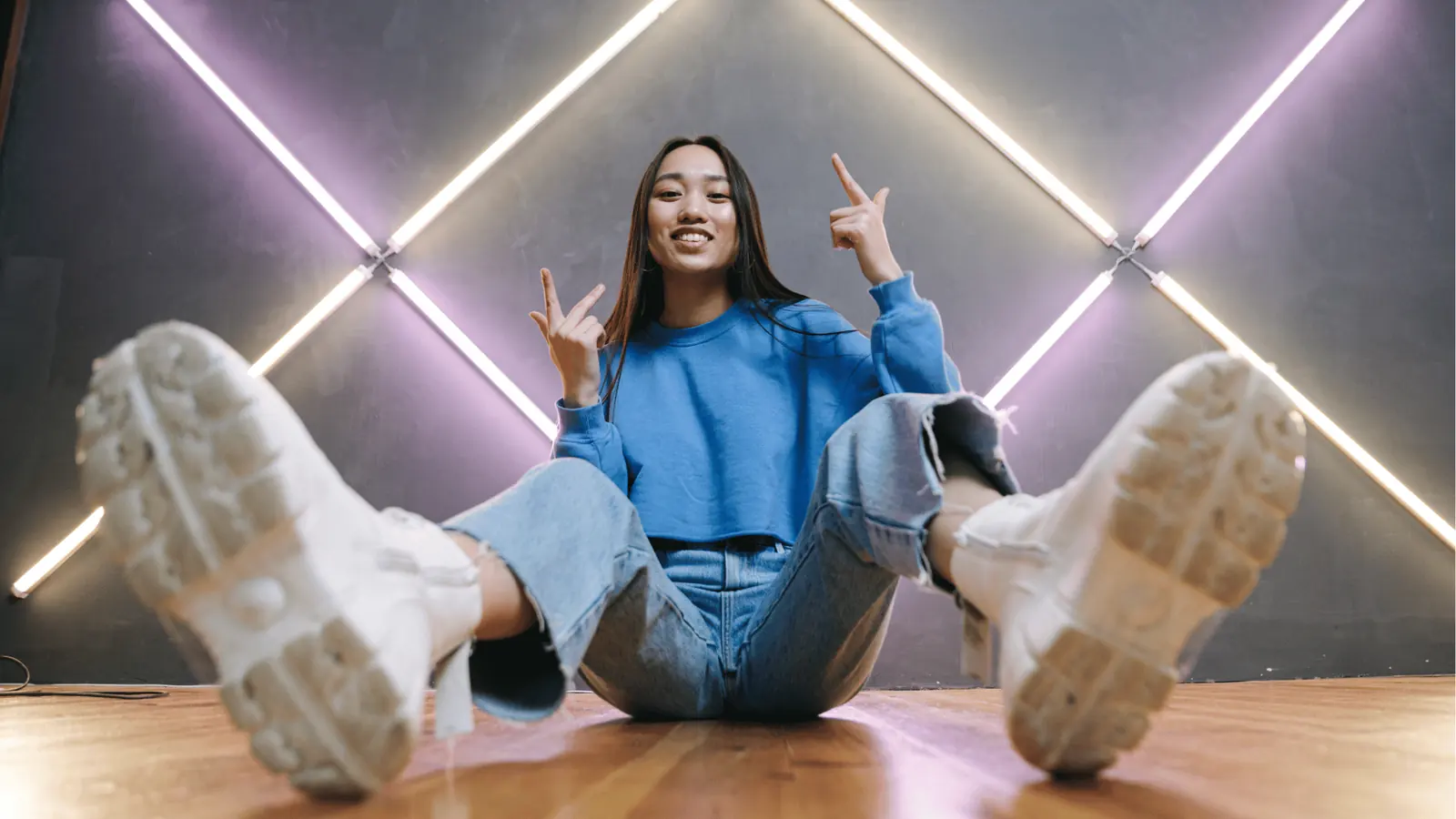 Low-angle portrait of a young woman sitting with sneakers toward camera