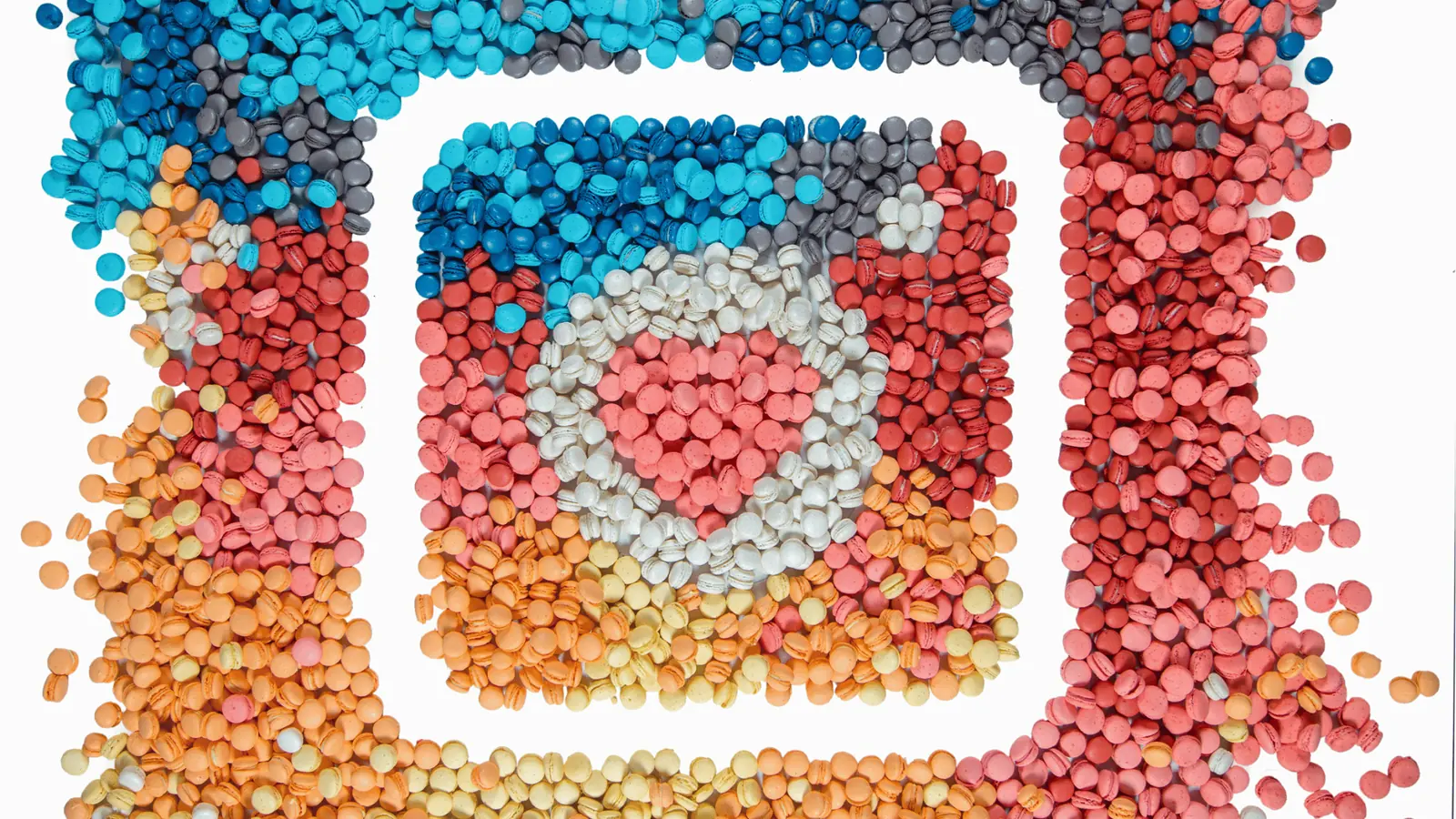 Top-down view of colorful macarons arranged as Instagram app icon on white for publishing