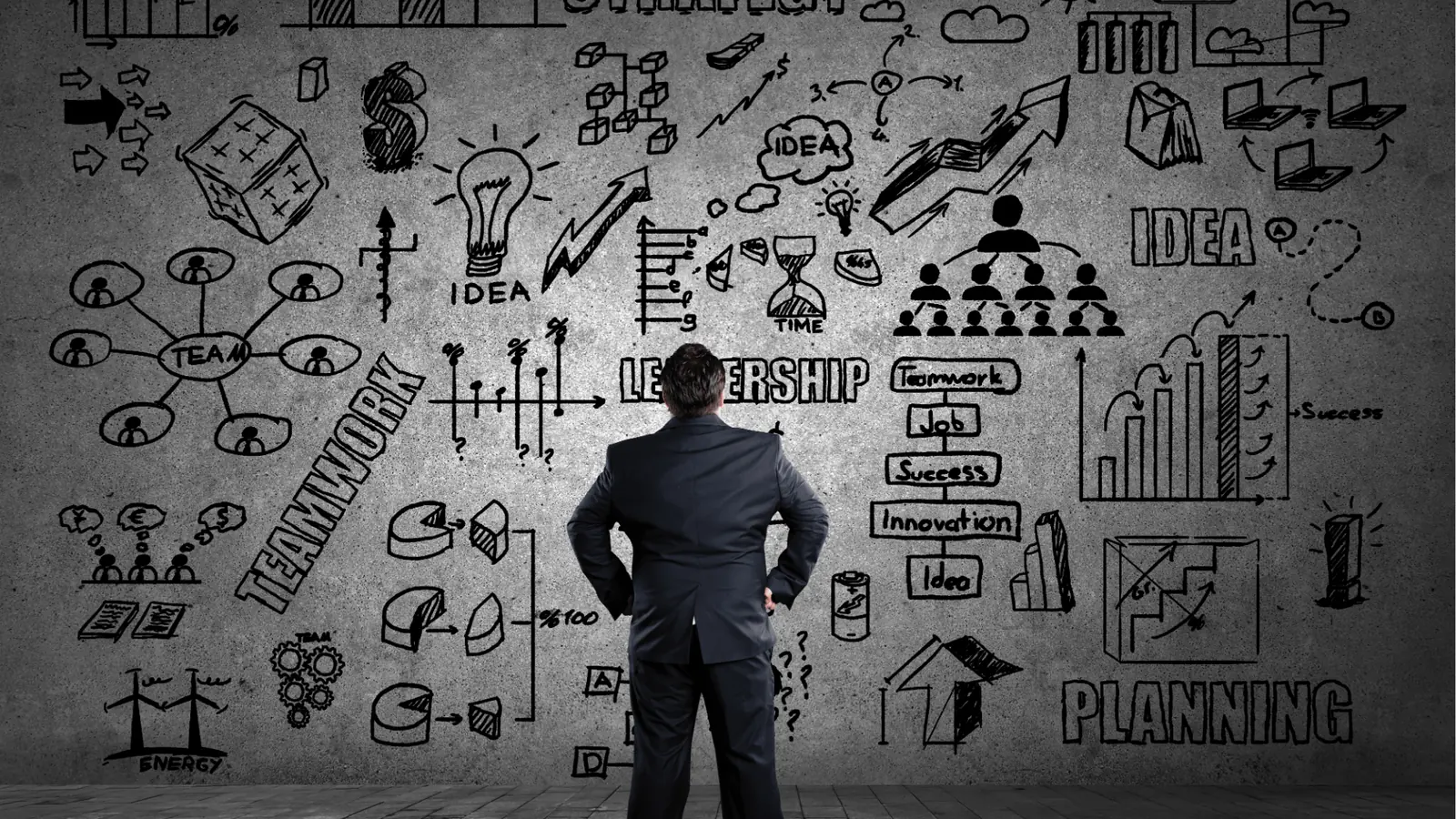 Man in suit facing concrete wall filled with business sketches and charts for approval workflow