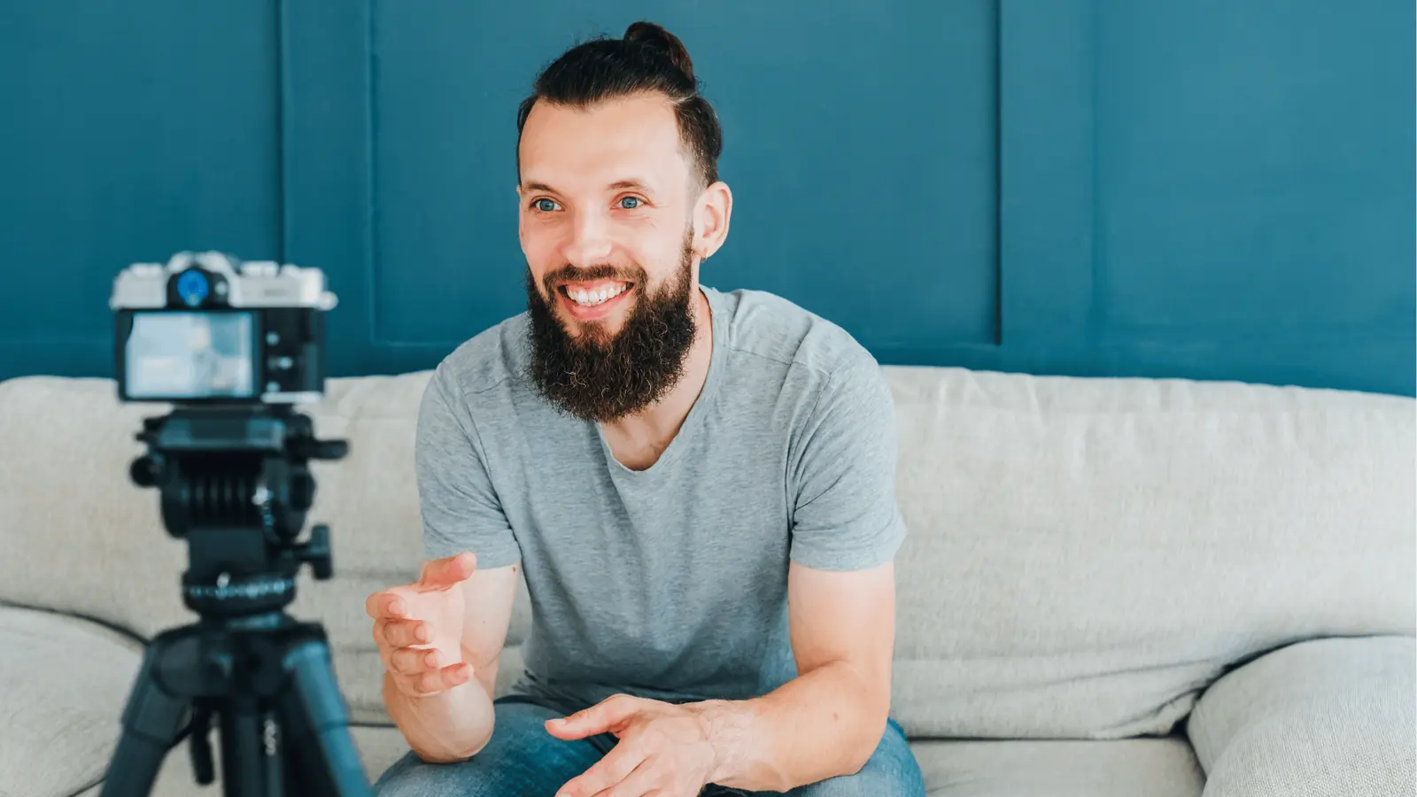 Bearded man sitting on sofa talking to camera mounted on a tripod for scheduling