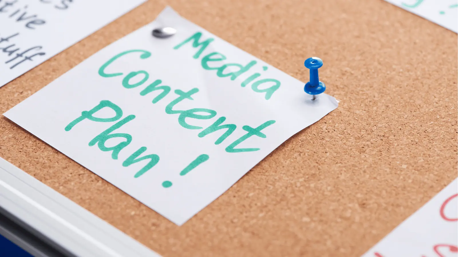 Close-up of corkboard with pinned note reading 'Media Content Plan!' and blue pushpin for brand management