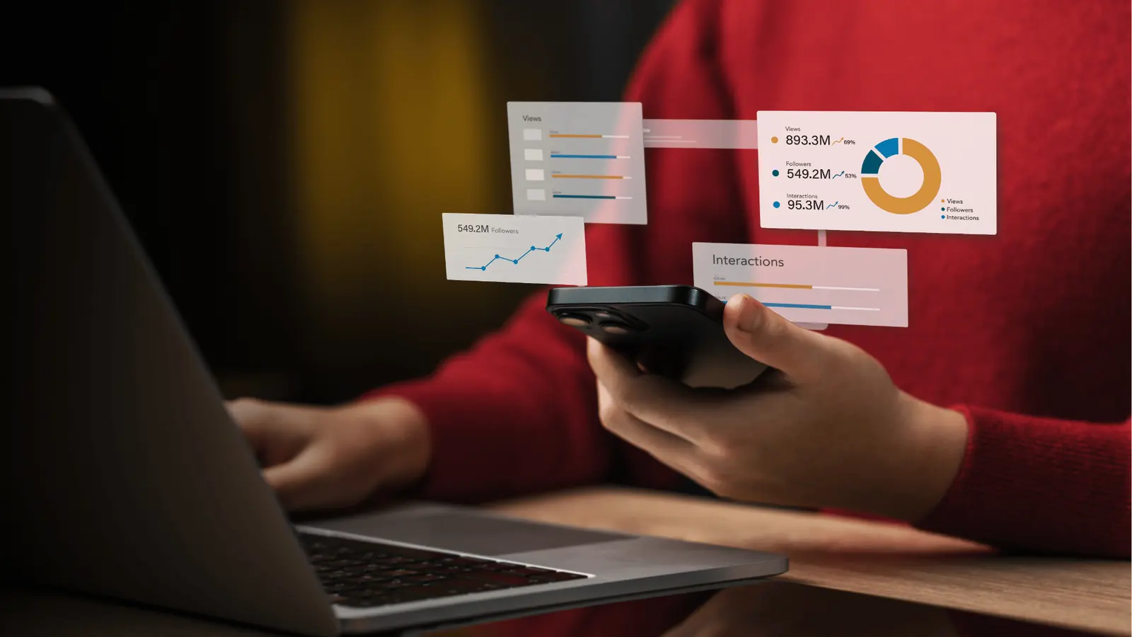 Person holding smartphone beside laptop with floating analytics charts for AI-assisted workflow