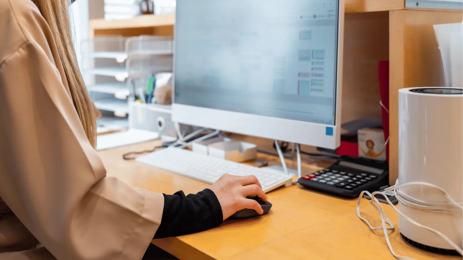 Person using a computer mouse at a desk with monitor and keyboard