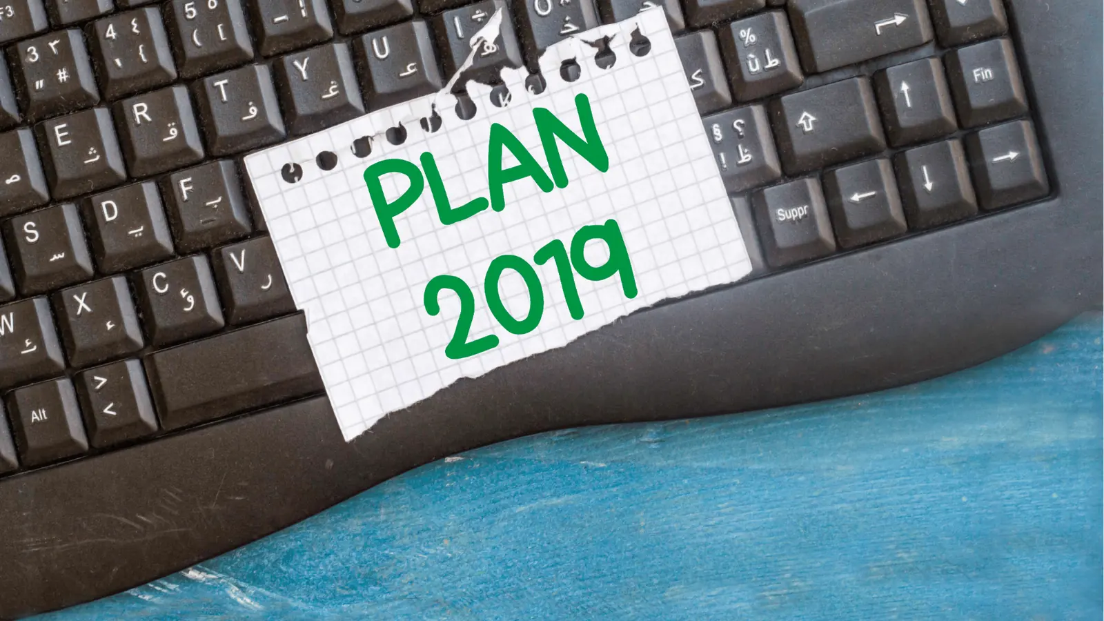 Torn graph paper reading PLAN 2019 placed on a black computer keyboard