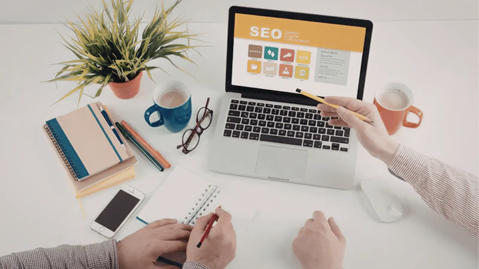 Overhead view of two people working at desk with laptop showing SEO screen for publishing