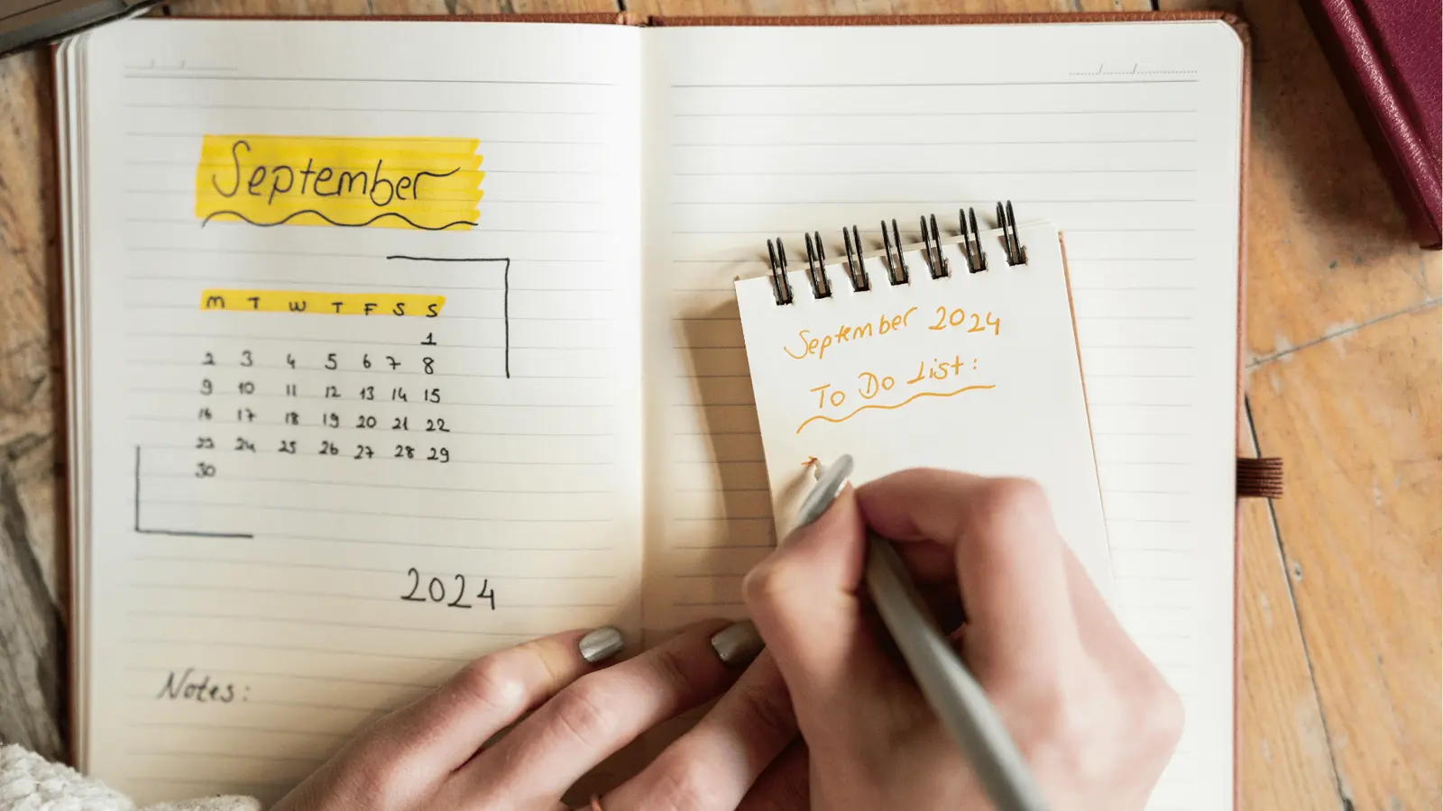 Person writing a September 2024 to-do list next to a notebook calendar for content calendar