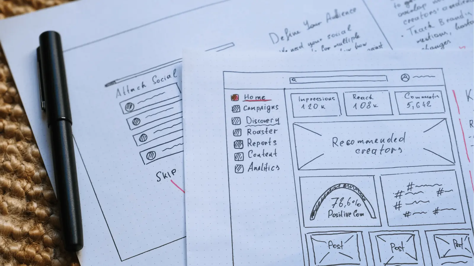 Top-down photo of hand-drawn social dashboard wireframe sketches with pen for publishing