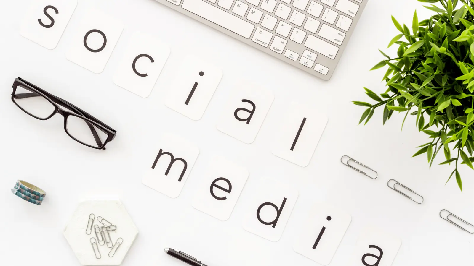 Flat lay desk with letter cards spelling social media and office items for asset management