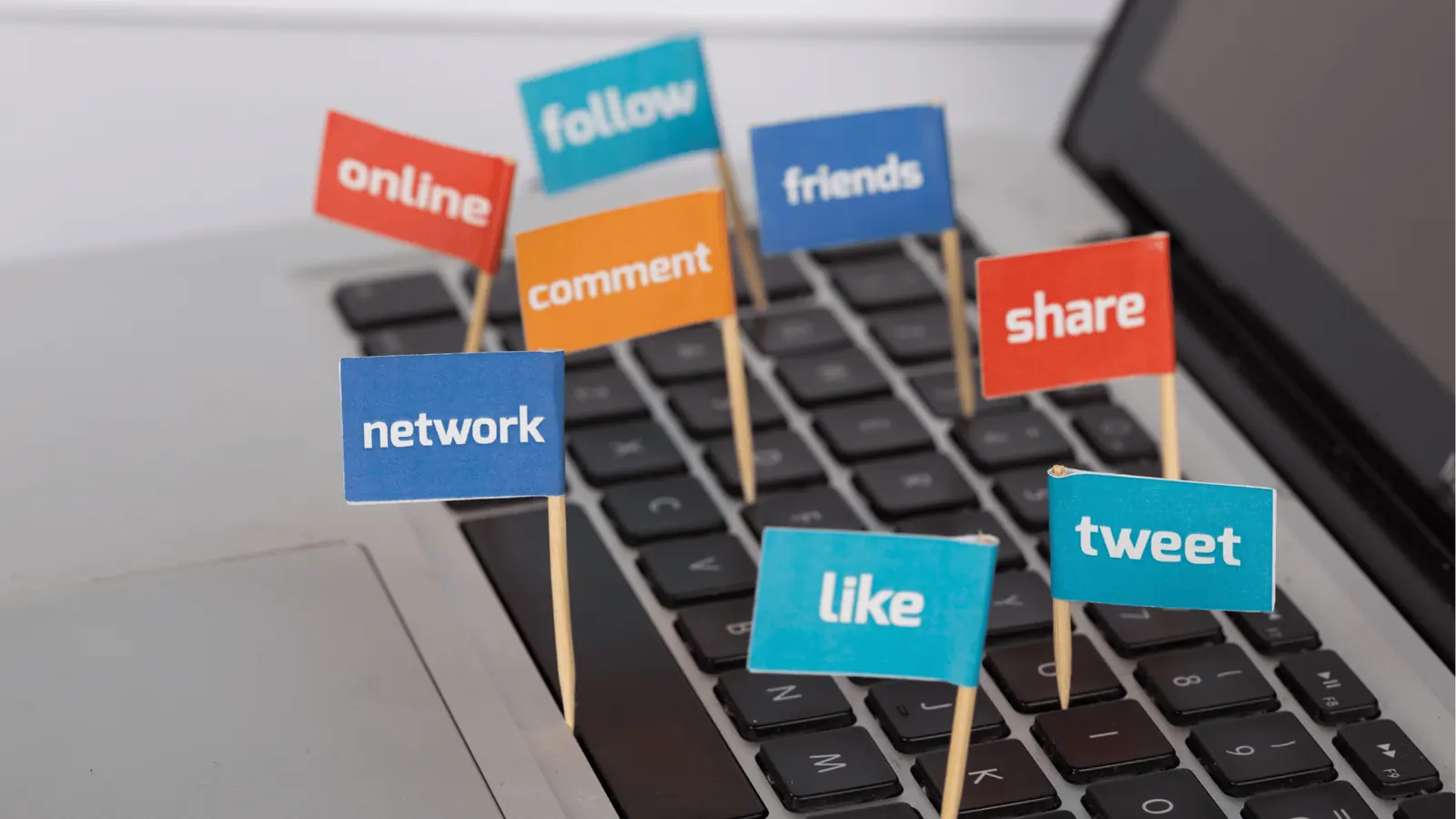 Small toothpick flags with social words stuck in laptop keyboard