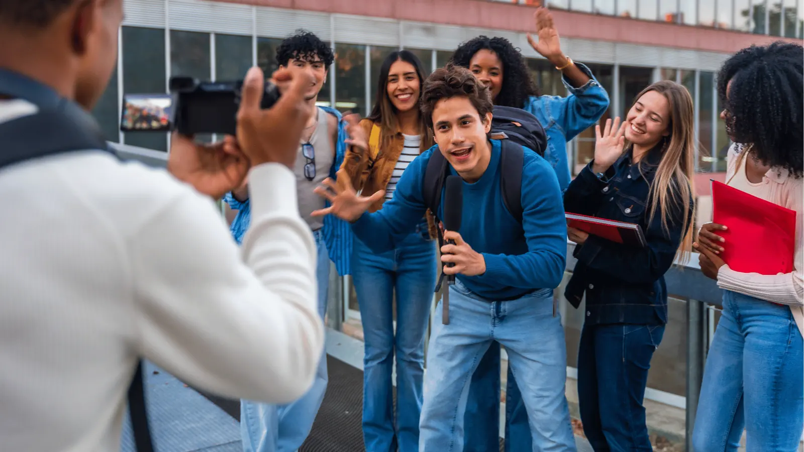 Group of college students filming a student vlogger with microphone and camera