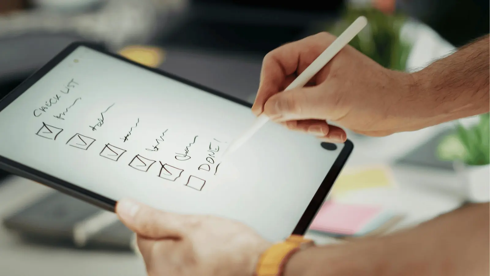 Hands using a stylus on tablet to check items on digital checklist