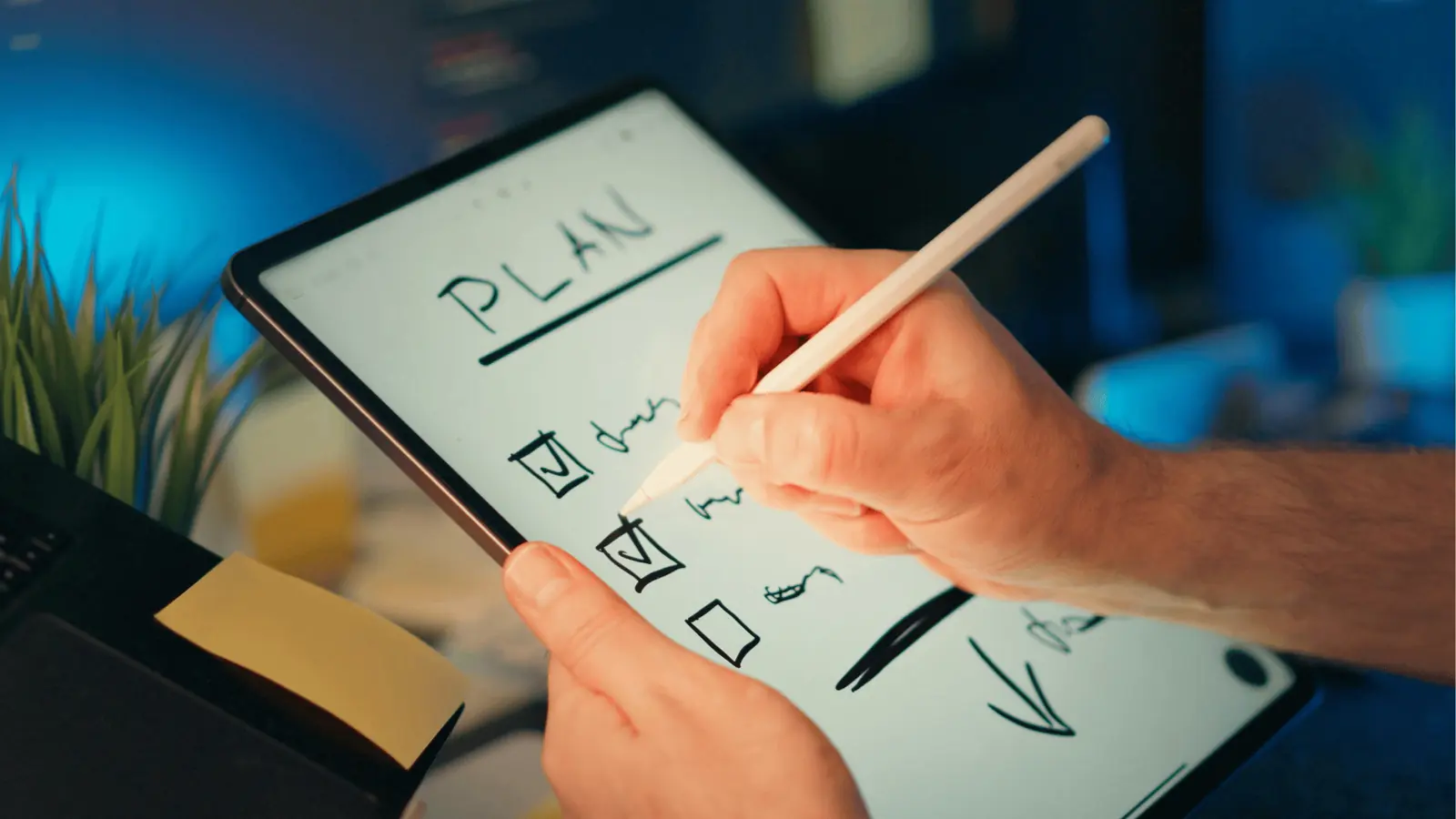 Hands using stylus on tablet writing a checklist titled PLAN