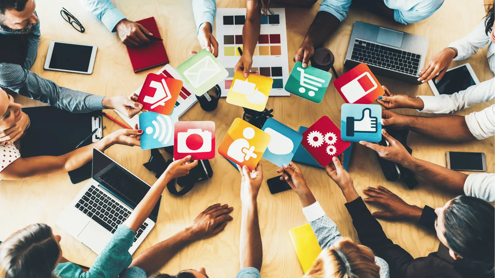 Overhead view of a team holding colorful social media and app icon cards for brand management
