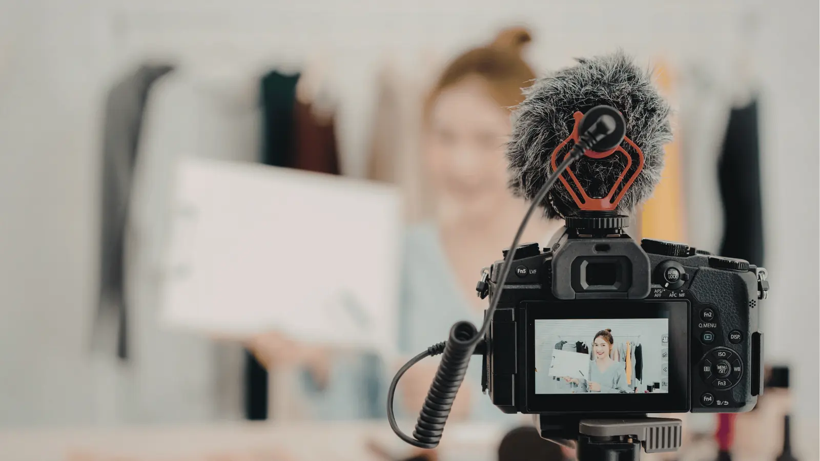 Camera with microphone filming a woman holding a product in studio