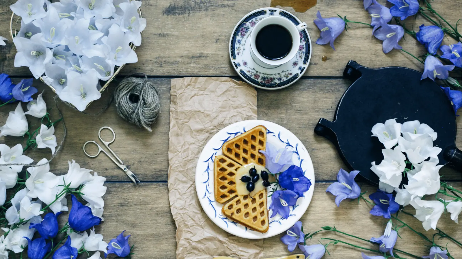 Flat lay of waffles on plate with coffee and purple and white flowers