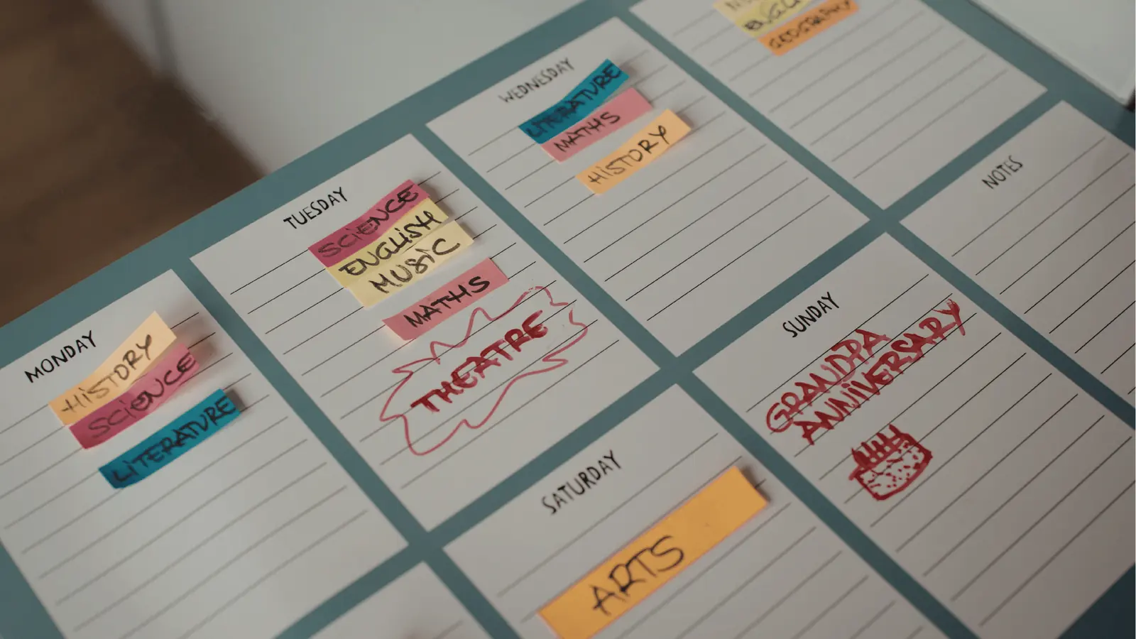 Overhead weekly planner with sticky subject notes and handwritten anniversary reminder