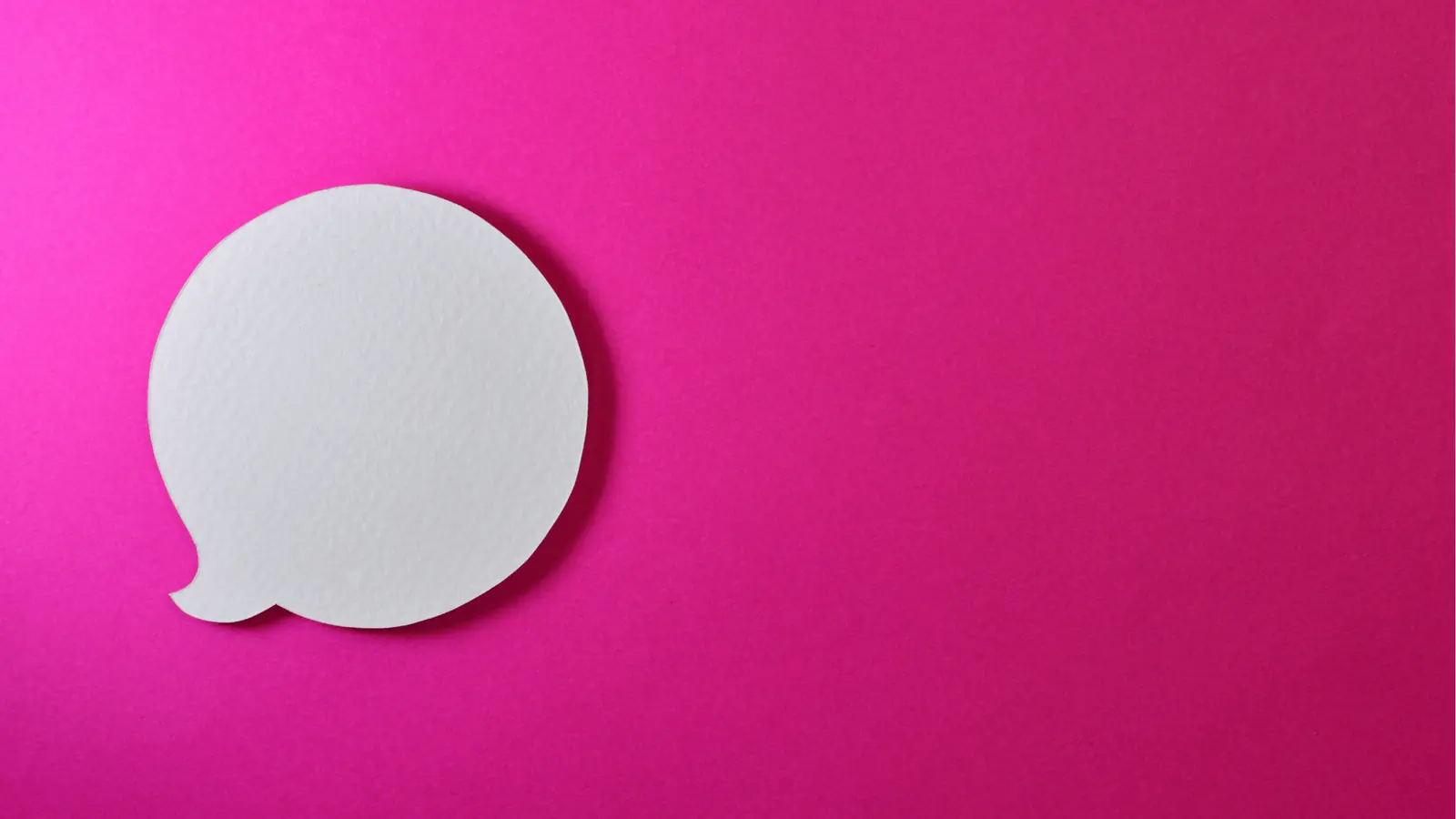 White paper speech bubble cutout on bright pink background with empty copy space