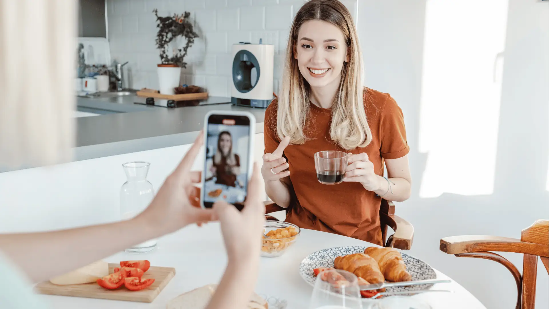 Woman smiling at camera while holding coffee during breakfast photoshoot