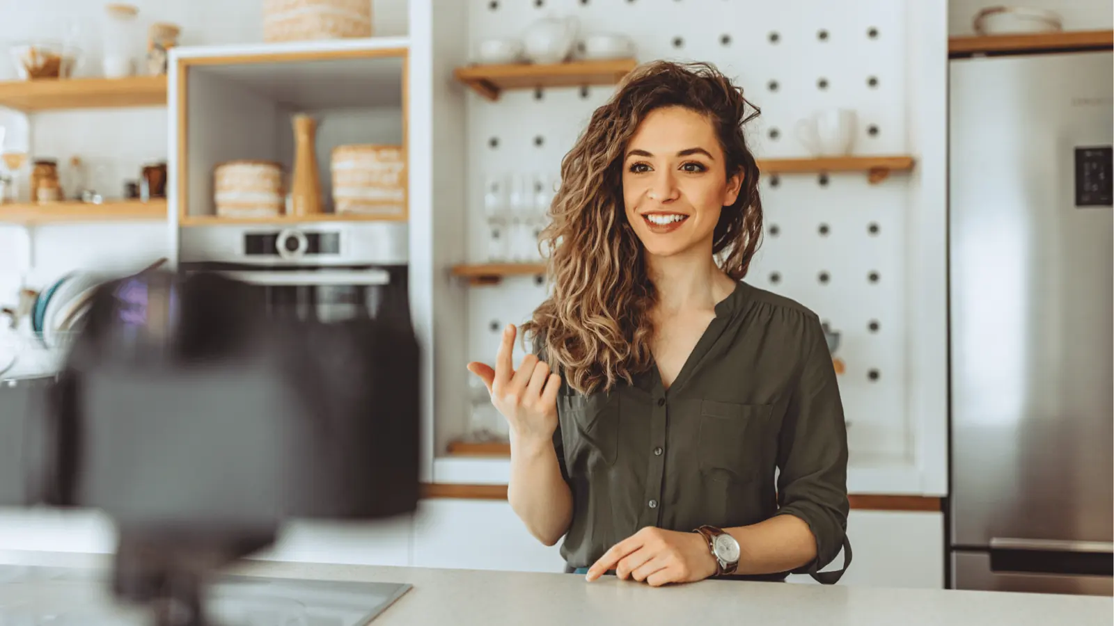 Smiling woman speaking to a camera while standing at a kitchen counter for content calendar