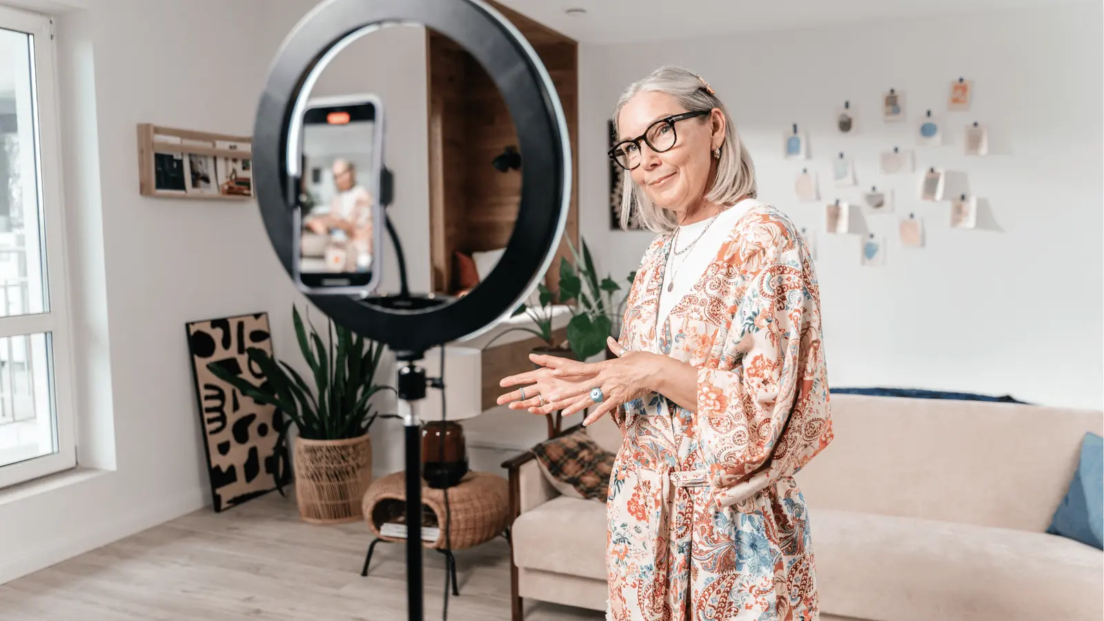 Older woman speaking to smartphone mounted in ring light in living room